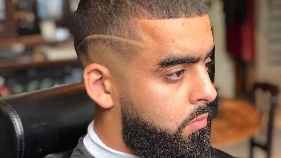 Close-up van een fade met een geschoren lijn in het haar en een volle, strak bijgewerkte baard